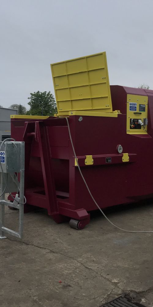 Gradeall GPC P24 portable wet waste compactor in custom purple and yellow, featuring a raised walkway with integrated remote controls and a hydraulic lid for easy manual loading.