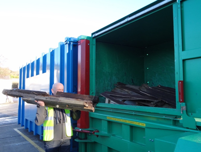 Rotten wood waste from garden furniture being thrown into the hopper of the G140 pre crusher compactor