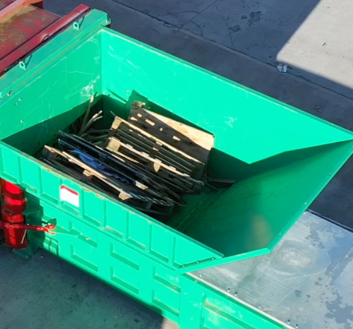Overhead view of waste wooden pallets inside the Gradeall G140 Pre-Crush Compactor's open top hopper.