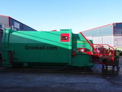 Green Gradeall GPC P24 wet waste compactor with red safety cage and bin lift, connected to power supply