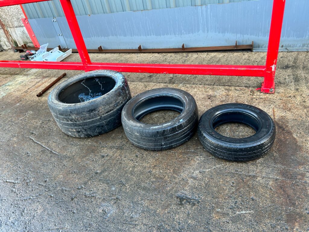 A variety of passenger vehicle tyres laid out, compatible with the Gradeall MK2 tyre baler.