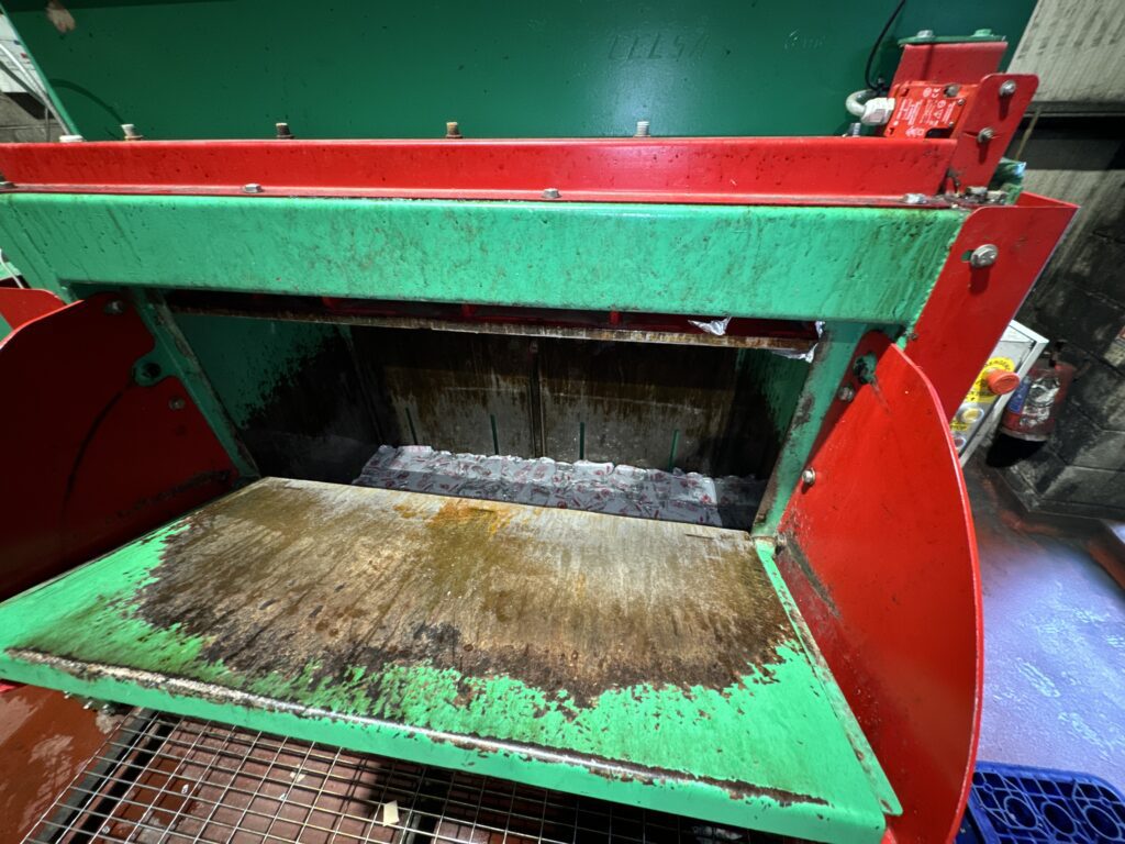 Close-up of the Gradeall GVC 750 baler mid-operation, crushing aluminium drink cans