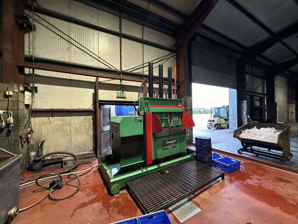 The Gradeall can baler positioned for operation in a spacious recycling facility.
