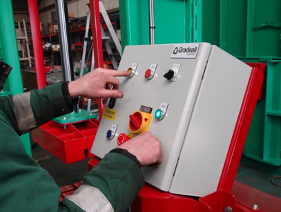 Close-up of an operator engaging the control panel of a Gradeall clothes baler, demonstrating the ease of operation