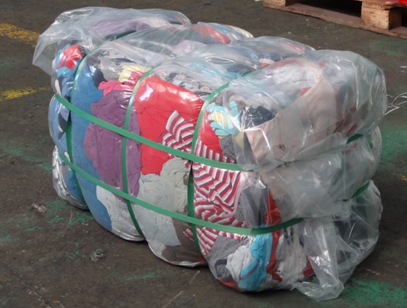 A bale of assorted textiles, tightly packed and wrapped, produced by a Gradeall clothes baler