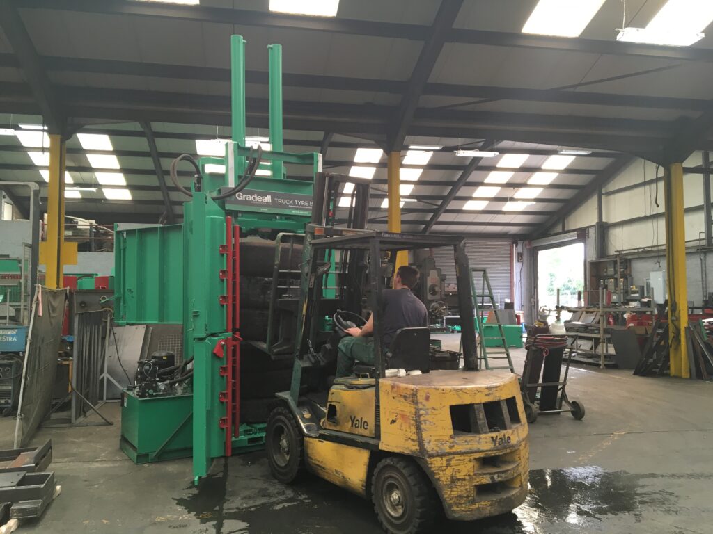 Forklift positioning truck tyres for compacting in a Gradeall Truck Tyre Baler