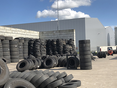 Stacks of loose truck tyres ready for baling at a recycling plant.