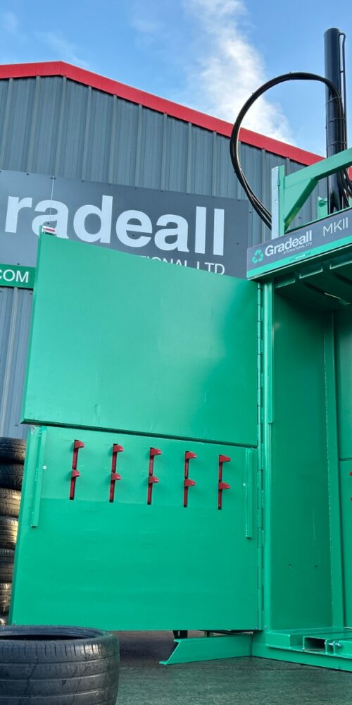 Worker loading tyres into the Gradeall MKII Tyre Baler in front of the gradeall facility.