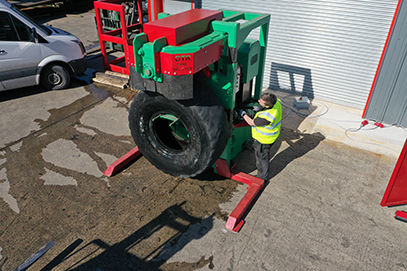 Worker operates the OTR tyre splitter, positioning a tyre for cutting