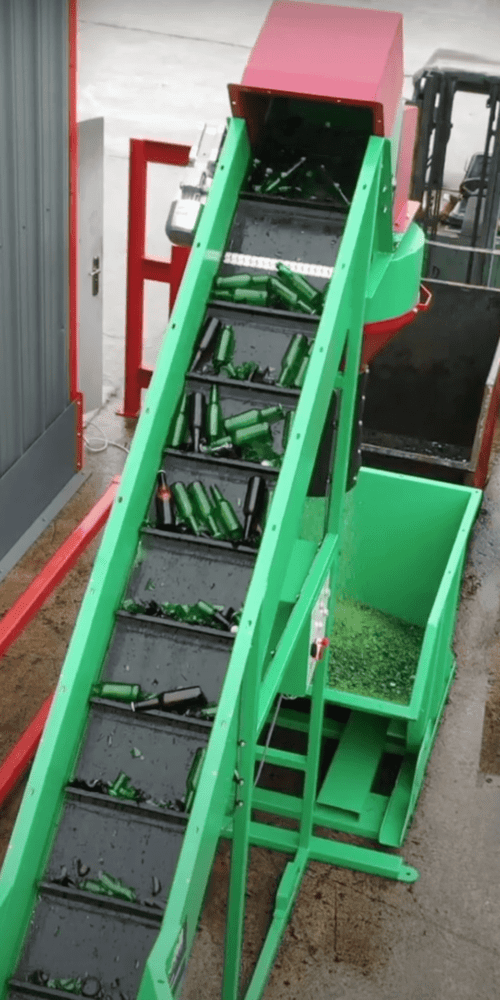 Glass bottle waste going through industrial glass crusher manufactured by Gradeall International