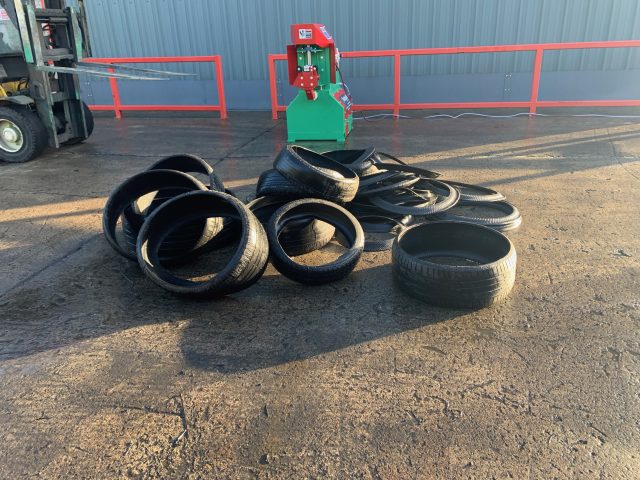 Gradeall Car Tyre Sidewall Cutter with a pile of neatly cut tyres in front