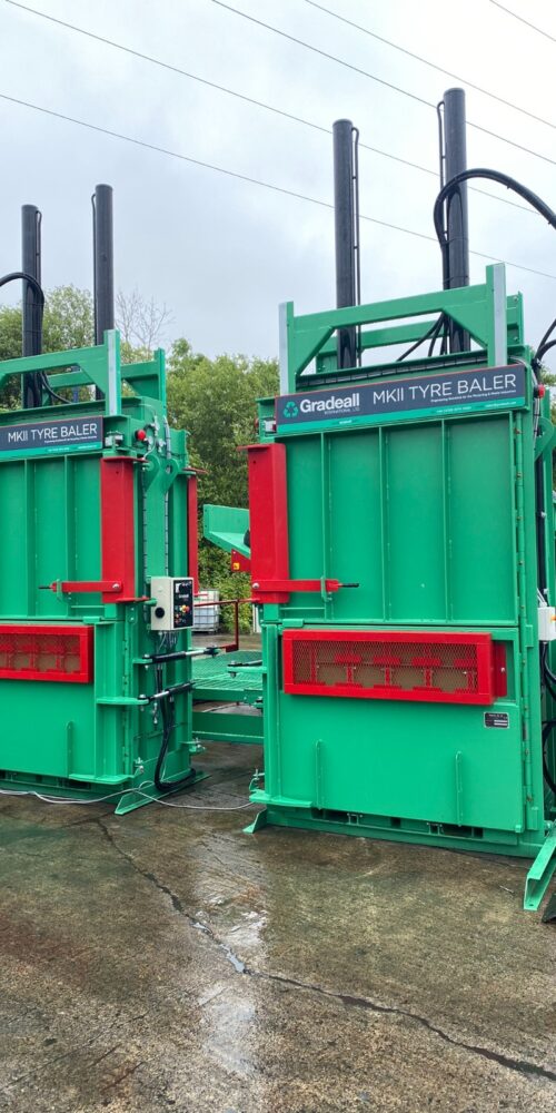 Two MK2 tyre balers with an inclined tyre baler conveyor on a wet concrete floor, showcasing the green and red machinery.