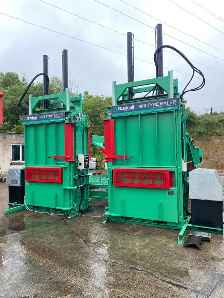 Two MK2 tyre balers with an inclined tyre baler conveyor on a wet concrete floor, showcasing the green and red machinery.