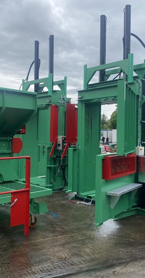 Photo of two MK2 tyre balers in front of an inclined tyre baler conveyor in an outdoor industrial setting.