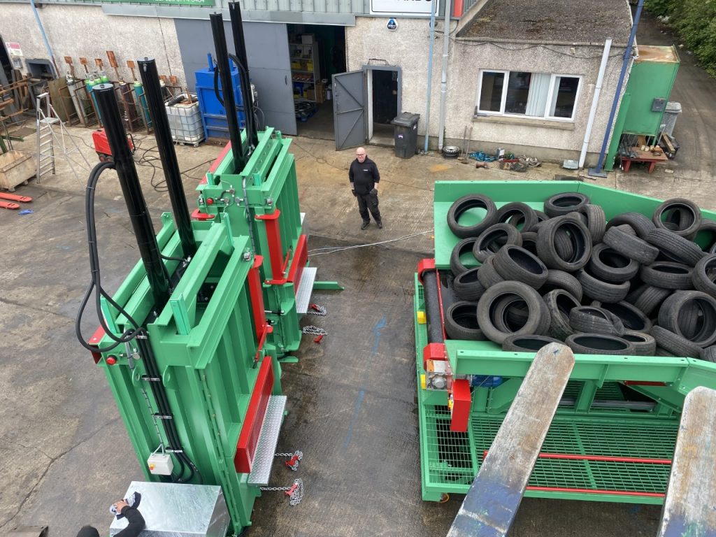 Overhead view of a Gradeall inclined tyre baler conveyor system in an industrial yard, highlighting the comprehensive setup for tyre recycling.