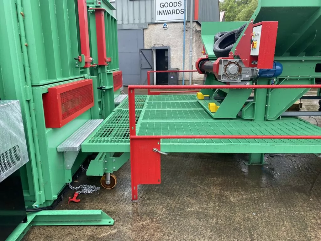 Detailed view of the Gradeall Inclined Tyre Baler Conveyor with its sturdy platform, safety handrails, and foot-operated control mechanism